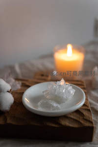 白瓷碟盛放晶莹矿石晶体，背景柔光蜡烛与棉絮营造冥想氛围