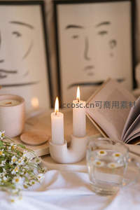 温馨烛光阅读角：雏菊、书本与抽象人脸画作静物组合