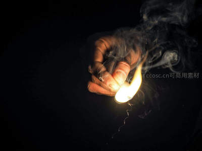 黑暗中点燃的火柴：手部特写与袅袅青烟的戏剧性光影