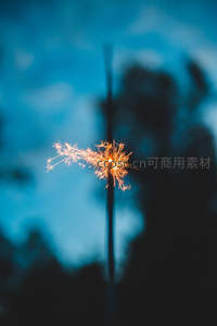 手持烟花棒在蓝调夜空下绽放火花，动态光影交织
