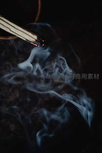 微距特写燃烧的线香，烟雾缭绕如丝，暗夜中红烬微光闪烁