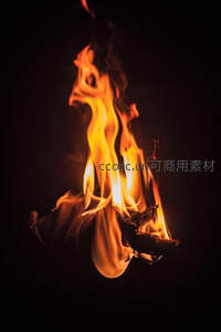 戴手套的手紧握燃烧木枝，火焰缠绕指间，危险与掌控并存