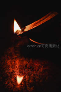 火柴点燃瞬间特写，微光映照粗糙木质与烟缕升腾
