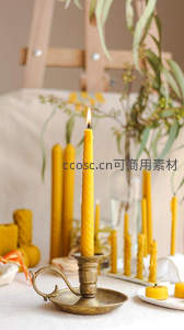 黄蜡烛静置于古铜烛台，搭配干花绿植营造温馨艺术氛围