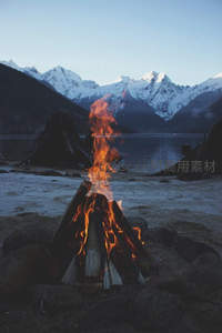 雪山湖畔篝火夜景，温暖火焰映衬壮丽雪峰倒影
