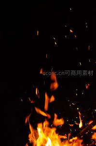 夜幕下篝火迸发火星，橙红光点如萤火升腾散落