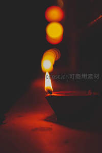 夜色中陶制油灯微光摇曳，背景暖色光斑朦胧梦幻