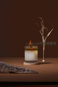 极简风香薰蜡烛配干草枝与枯木，暖棕背景凸显质感与留白美学