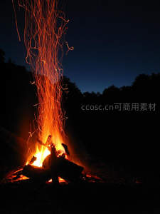 夜幕下篝火升腾，炽热火星如流星雨划破深蓝天幕