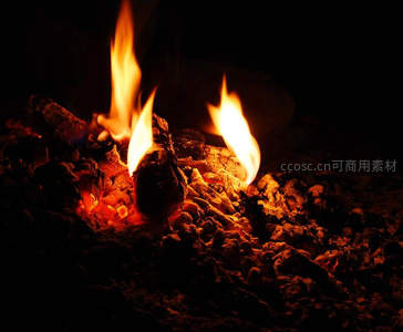 夜色中燃烧的木炭余烬，橙红火焰跃动映照灰白炭渣纹理