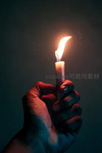 黑暗中紧握燃烧蜡烛的手，微光映照掌纹与希望