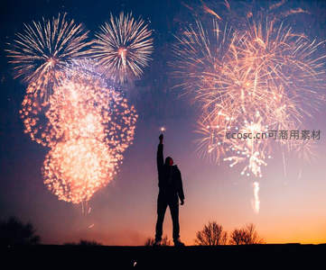 剪影人举手仰望绚烂烟花，暮色天幕绽放金色光雨