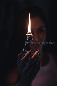 手持燃烧灯泡的神秘女子，幽暗中光明与科技的诗意隐喻