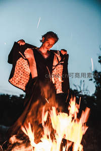 青年男子立于篝火前，掀开和风外套展露内衬