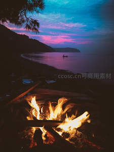 海边篝火映晚霞，孤舟静泊海岸线，松影剪影入画