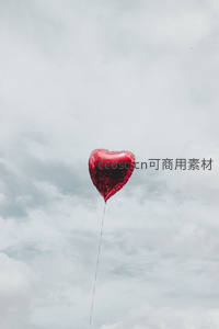 红色心形气球独悬云空，浪漫孤寂交织诗意瞬间