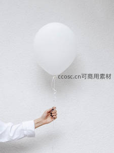 素手轻握纯白气球，极简墙面映衬宁静仪式感
