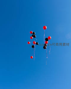 红黑气球成簇升空于纯净蔚蓝天空极简构图