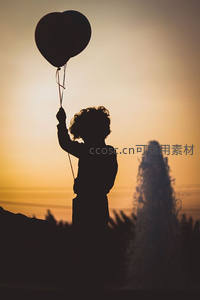 夕阳下孩童手握气球剪影，喷泉旁童真瞬间定格