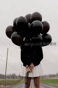 乡间公路上少女怀抱黑色气球束，阴天静谧情绪影像