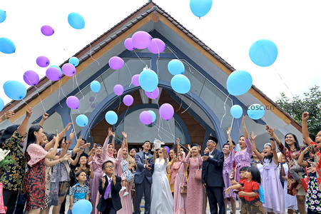 婚礼现场集体放飞气球：新人与宾客欢笑中释放蓝紫气球庆祝幸福时刻