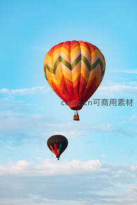 彩绘热气球翱翔蓝天，几何图案绚丽夺目，云朵轻柔相伴