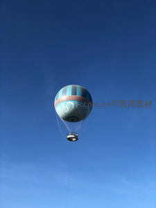 蓝白条纹热气球翱翔于澄澈蓝天之中