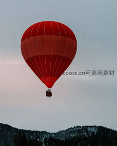鲜红热气球掠过雪岭松林，暮色苍茫中载客悠然升空
