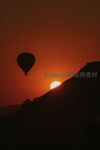 剪影热气球伴日落山脊：橙红天幕下，孤影与初升夕阳共舞
