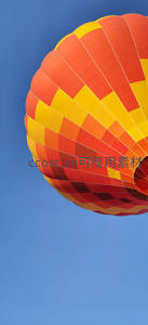 橙黄条纹热气球仰拍特写，湛蓝天空下色彩鲜明饱满