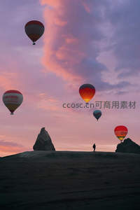 紫霞满天中热气球巡游，孤影旅人伫立奇岩之巅仰望苍穹