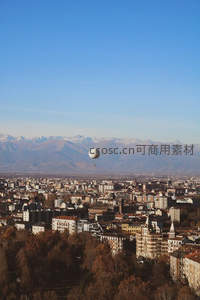 热气球翱翔城市上空，远山如黛映衬秋日都市风光