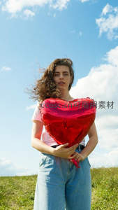 风中少女紧抱红色心形气球神情专注沉静