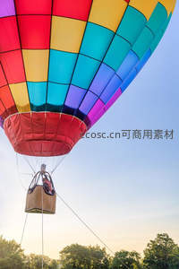多色方格热气球腾空而起，乘客俯瞰林海晨光