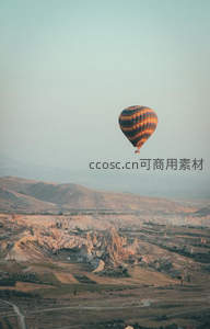 条纹热气球掠过卡帕多奇亚岩谷，晨光中地貌如火星般奇幻