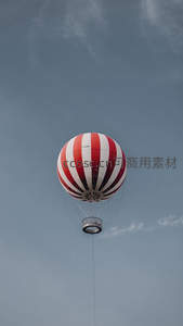 红白条纹热气球静悬灰蓝天空，简约线条与几何美感交织