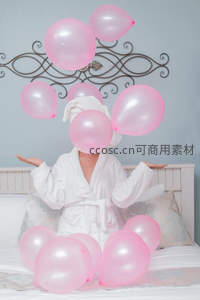 粉色气球环绕浴袍女子，轻松惬意的晨间休憩时光