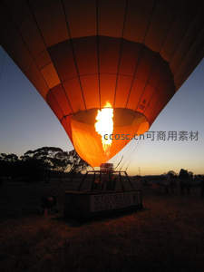 热气球燃烧器喷焰照亮暮色，地面准备升空前的炽热瞬间