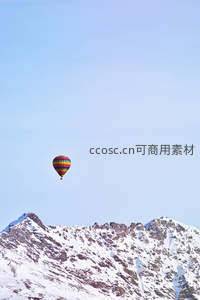 彩虹热气球孤悬雪峰之巅，纯净蓝天映衬壮丽高山地貌