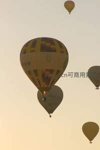 金色晨曦里多只热气球在淡黄天空中优雅飘浮