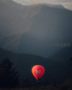 红色热气球静悬深谷前，层叠山峦在暮色中勾勒出苍茫剪影