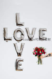 银色LOVE字母气球组合搭配鲜花束，手部持花浪漫呈现