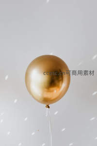 金色金属质感气球悬浮于光斑背景中，简约高级感十足