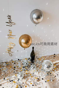 香槟瓶与镜面球点缀的跨年场景，金黑纸屑洒满地面