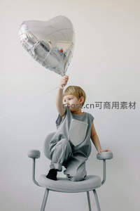 金发孩童高举银色心形气球，灰调极简风童趣写真