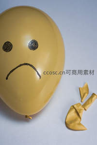 金色气球绘悲伤表情旁置破裂残片，象征失落与情绪隐喻