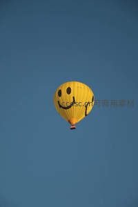 明黄色笑脸热气球高飞蔚蓝晴空，童趣与希望的空中符号