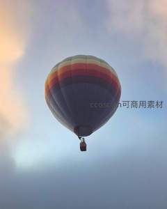 条纹热气球升空于暮色云层间，色彩渐变如油画般唯美