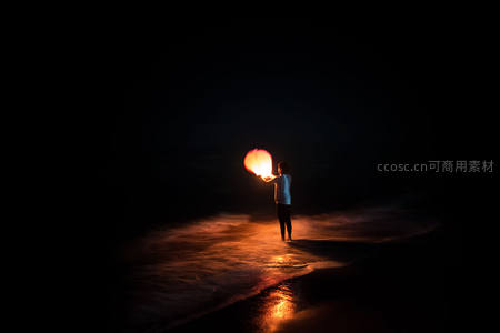 海边夜放孔明灯，一人静立潮汐光影间祈愿瞬间