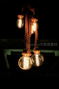 粗麻绳悬挂四盏复古爱迪生灯泡，黑暗中 filament 线圈清晰可见
